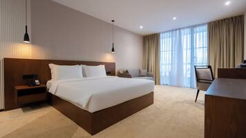 Una habitación de hotel moderna con una cama grande, mesitas de noche, un escritorio y una silla.