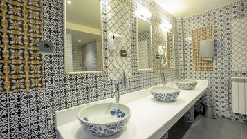 Un baño con baldosas estampadas, un mueble de tocador largo con tres lavamanos y un espejo.