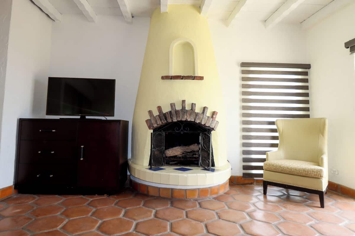 A living room with a fireplace, a television, a cabinet, and a chair.