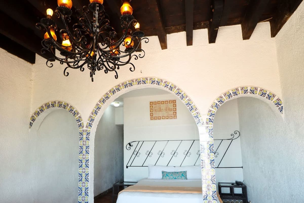 A room with a bed, a chandelier, and decorative arches.
