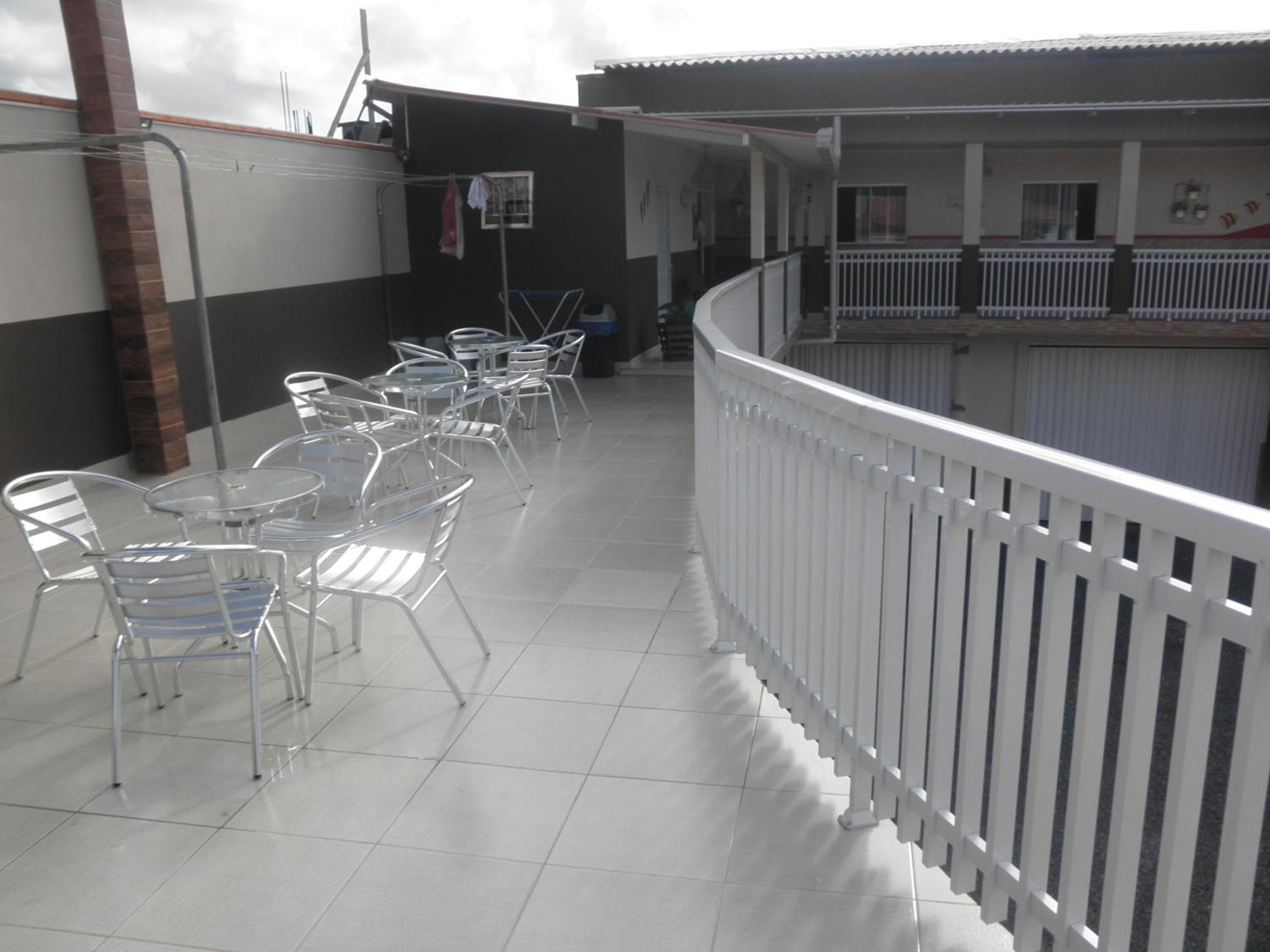 A balcony with white railings, metal chairs, and tables.