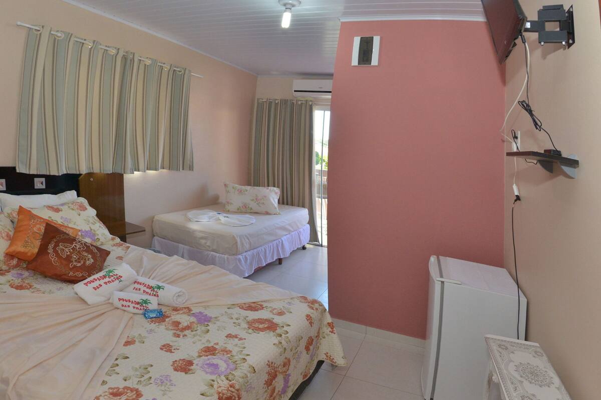 Una habitación de hotel con dos camas, una mesita pequeña y un armario blanco.