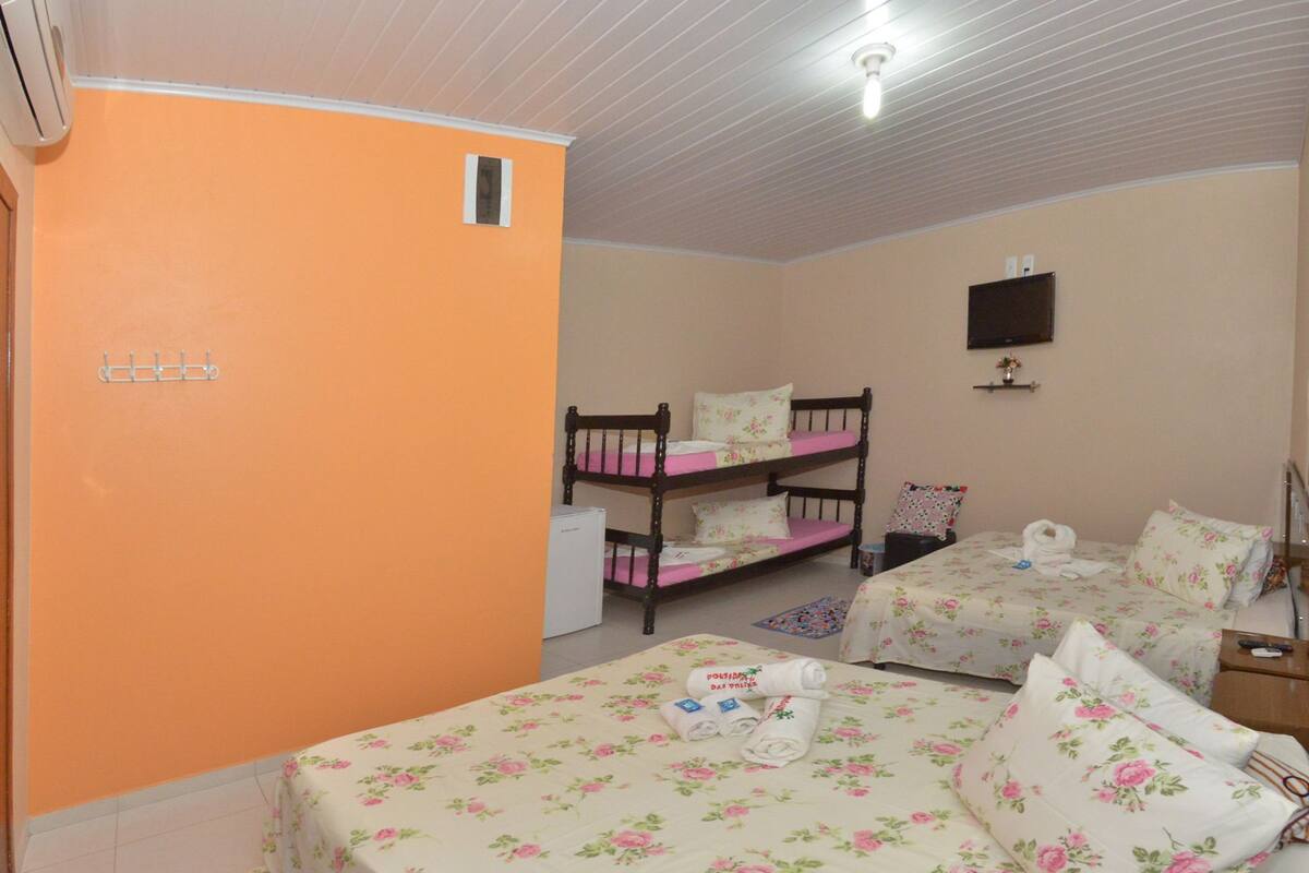 Una habitación con dos camas, una litera y una pequeña mesa.