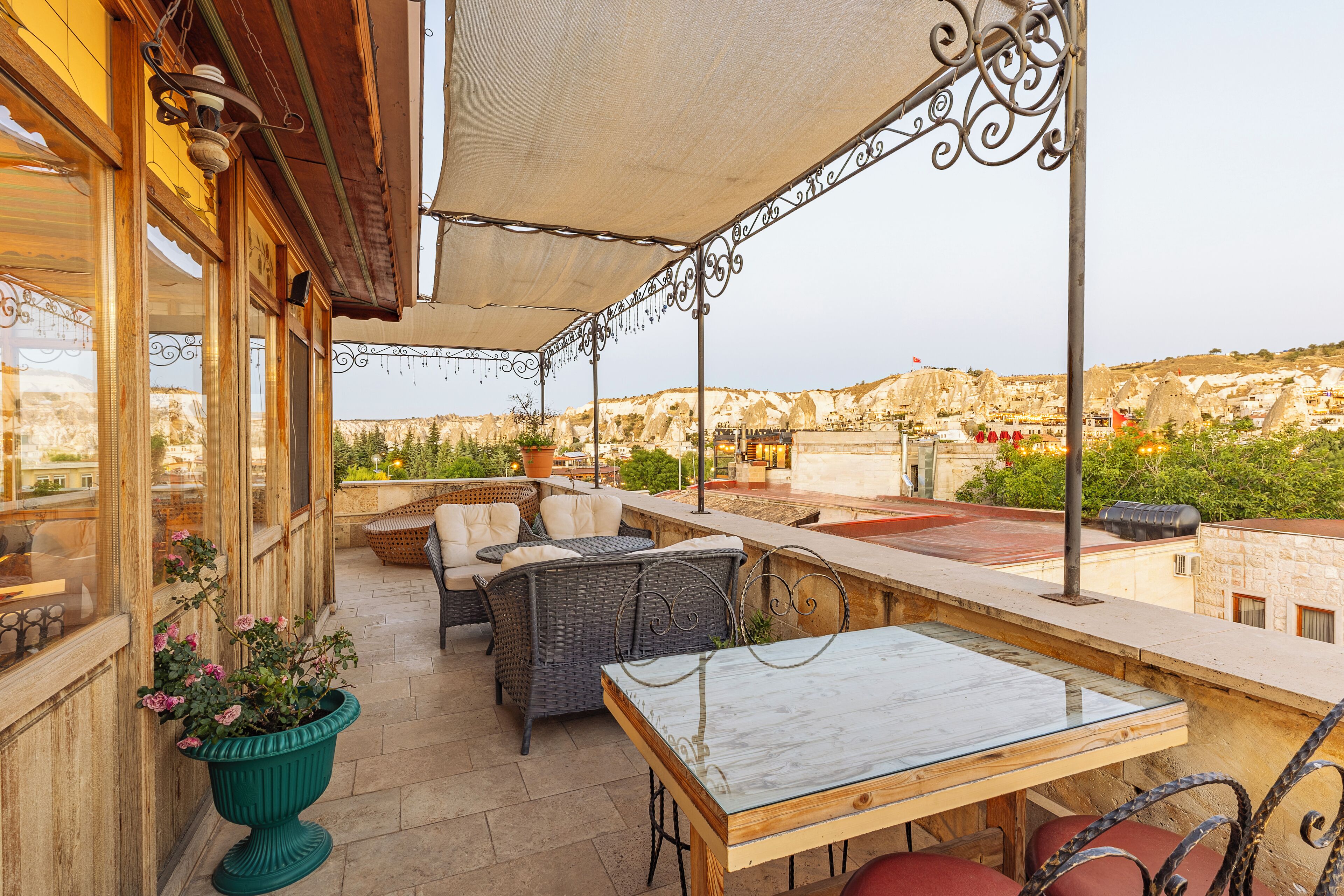 An outdoor patio area with wicker furniture, a marble table, and a view of a mountainous landscape.