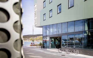 A modern building with large windows, a bike parked outside, and a view of a waterfront. - Smarthotel Hammerfest (Hammerfest)