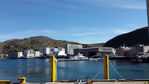 A harbor with buildings, a dock, and a mountain in the background. - Smarthotel Hammerfest (Hammerfest)