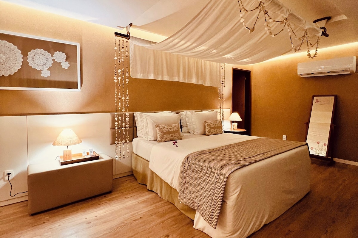 Quarto com cama, mesa de cabeceira e ar condicionado fixado na parede.