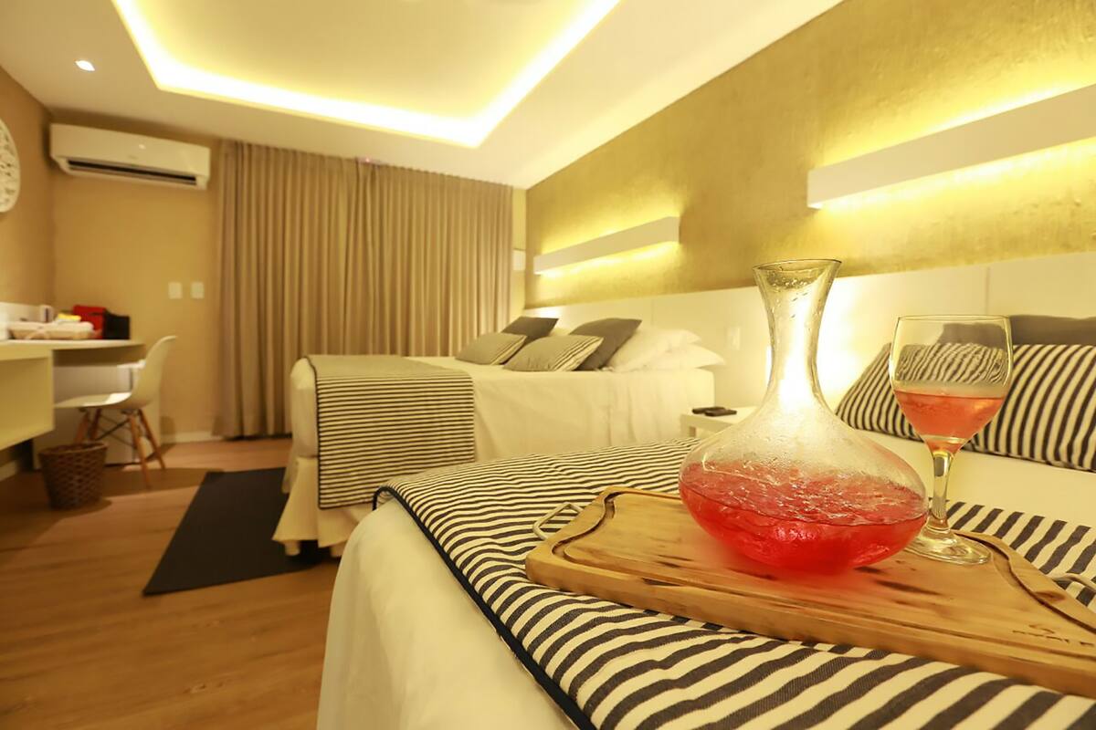 Quarto de hotel com uma cama, mesa de cabeceira e um pequeno espaço de trabalho.