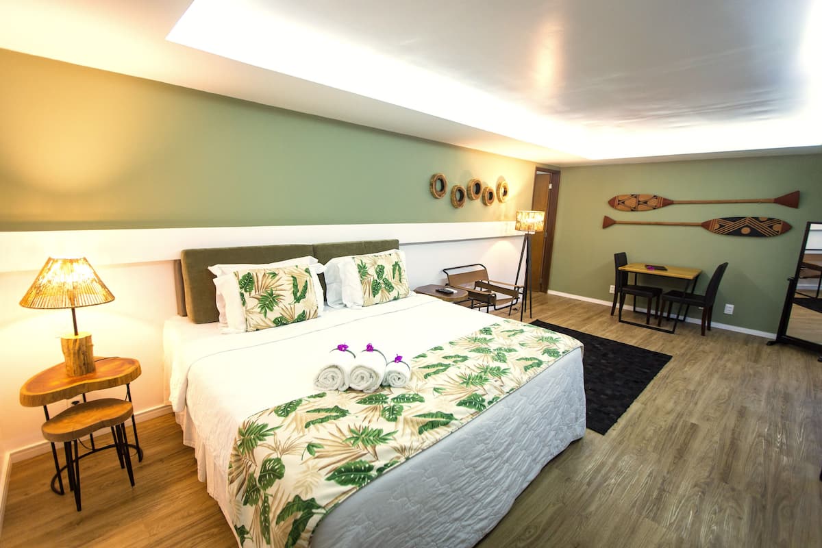 Quarto de hotel bem organizado, com uma cama, uma escrivaninha e uma cadeira.