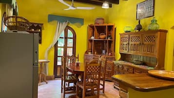 Una cocina con armarios de madera, una mesa de comedor, sillas y un refrigerador.
