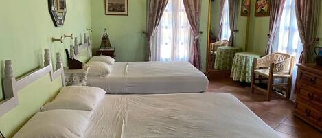 Une chambre avec deux lits, une commode en bois, une chaise et un climatiseur fixé au mur.