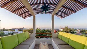 Un espace extérieur aménagé avec une terrasse couverte, une table en bois et des coussins, offrant une vue panoramique.