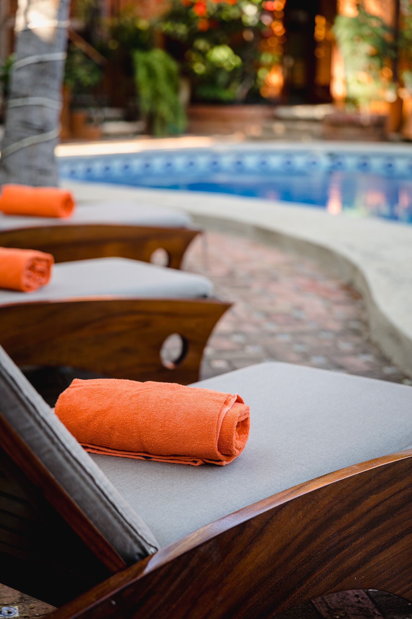 A poolside area with wooden loungers and orange towels.