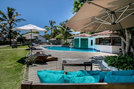 Una piscina al aire libre, sombrillas, sillones reclinables de piscina