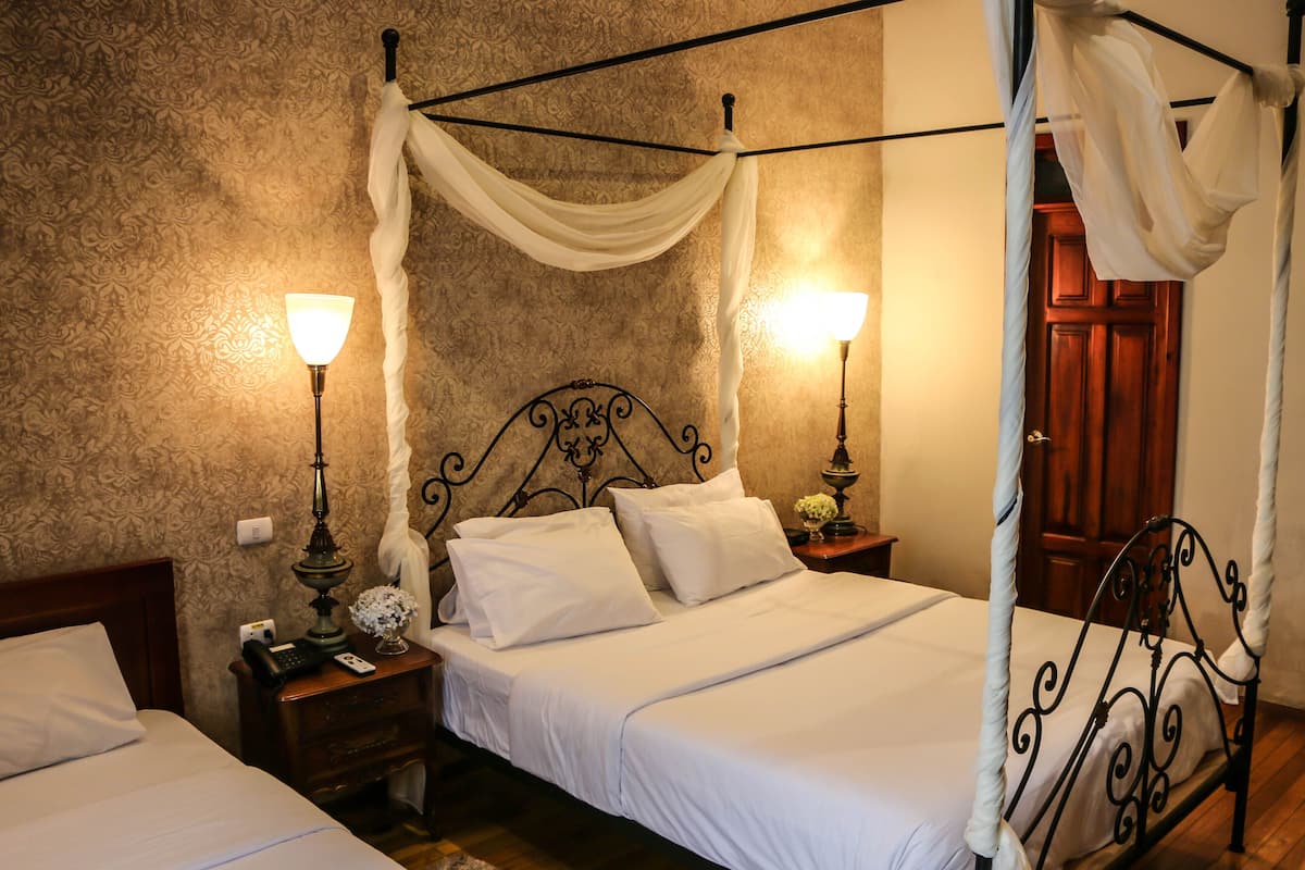 Une chambre à coucher avec un lit à baldaquin, deux tables de chevet avec des lampes et une porte en bois.