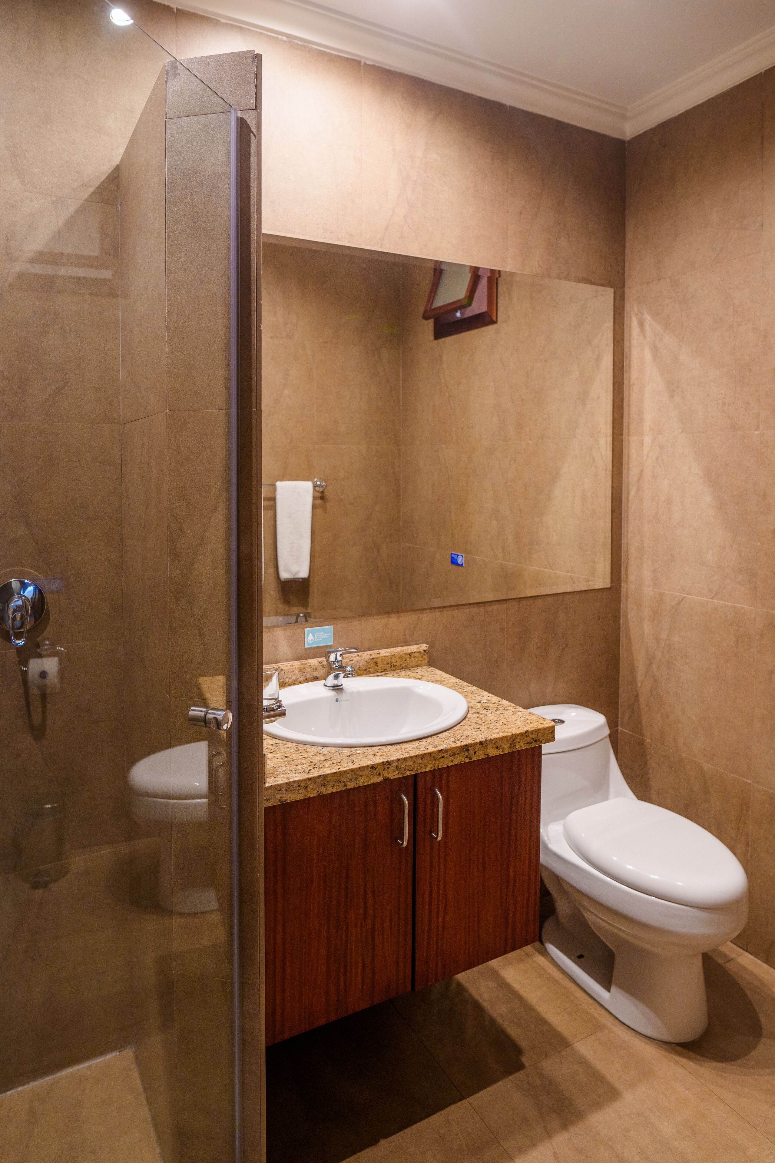 Un baño con cabina de ducha de vidrio, un lavamanos blanco y un inodoro.