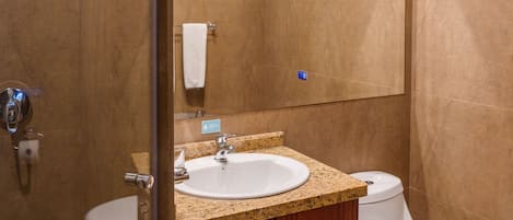 Un baño con cabina de ducha de vidrio, un lavamanos blanco y un inodoro.