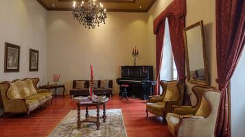 Amplia sala de estar con una imponente lámpara de araña, un piano y muebles clásicos.