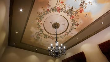 A chandelier with multiple lights hanging from the ceiling, surrounded by floral and bird designs.
