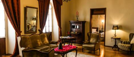 Un salon traditionnel avec un canapé, des fauteuils, une table basse et un lustre.
