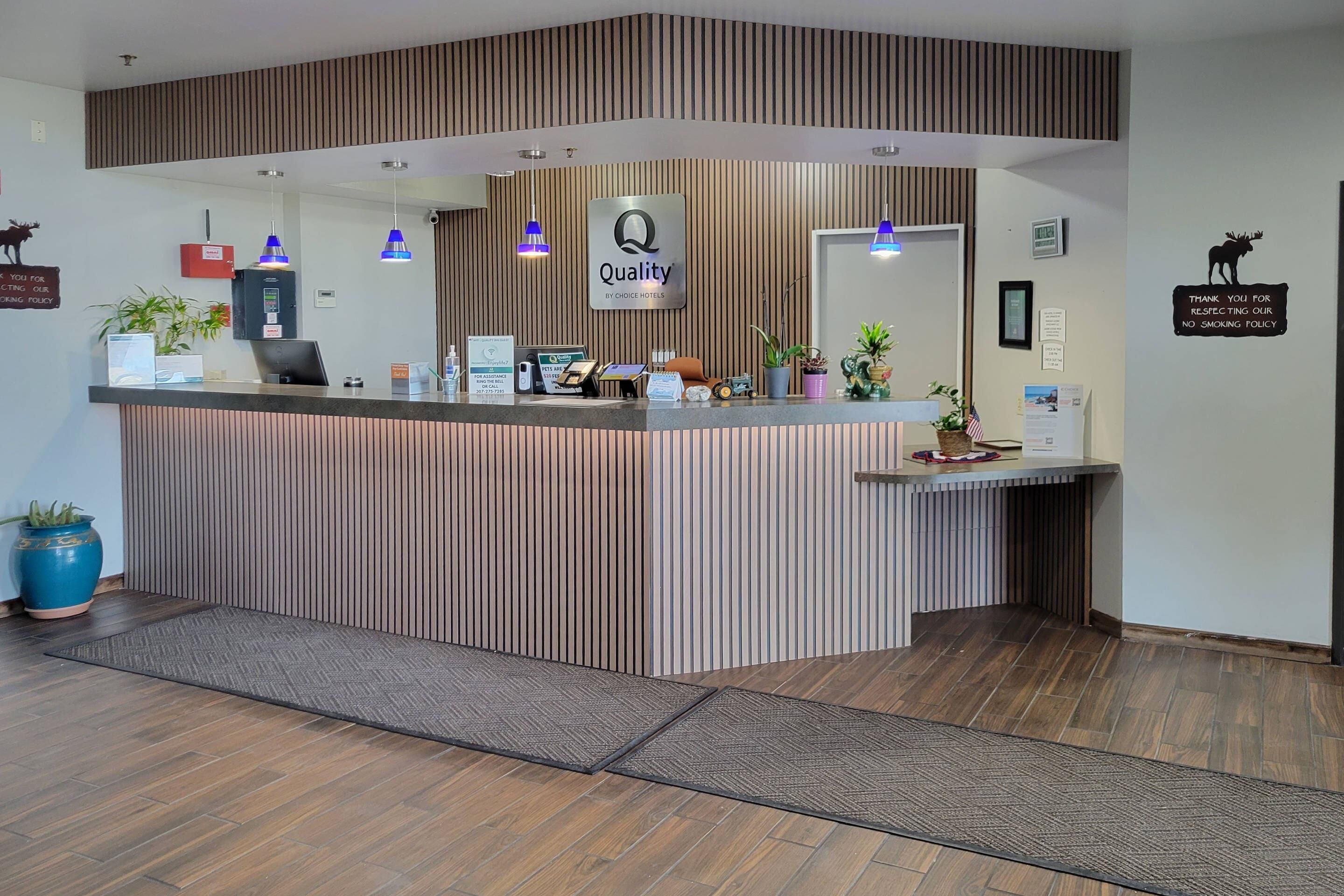A reception desk with a 'Quality by Choice Hotels' sign, a no-smoking sign, and a moose decoration.