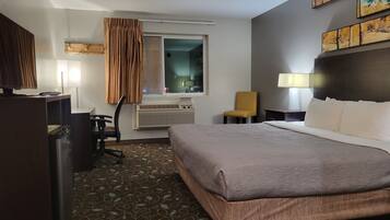 Una habitación de hotel con cama, escritorio, silla y ventana.