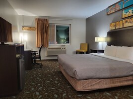 Una habitación de hotel con cama, escritorio, silla y ventana.