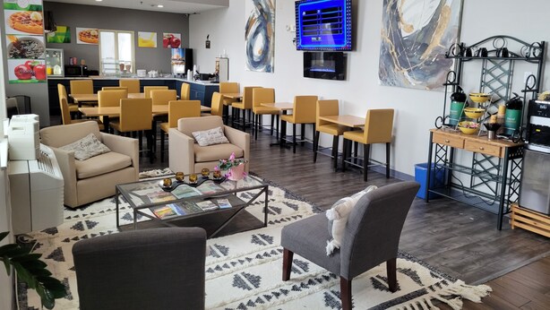 A modern lounge area with multiple seating options, a coffee station, and a television mounted on the wall. - Quality Inn & Suites Pinedale (Pinedale)