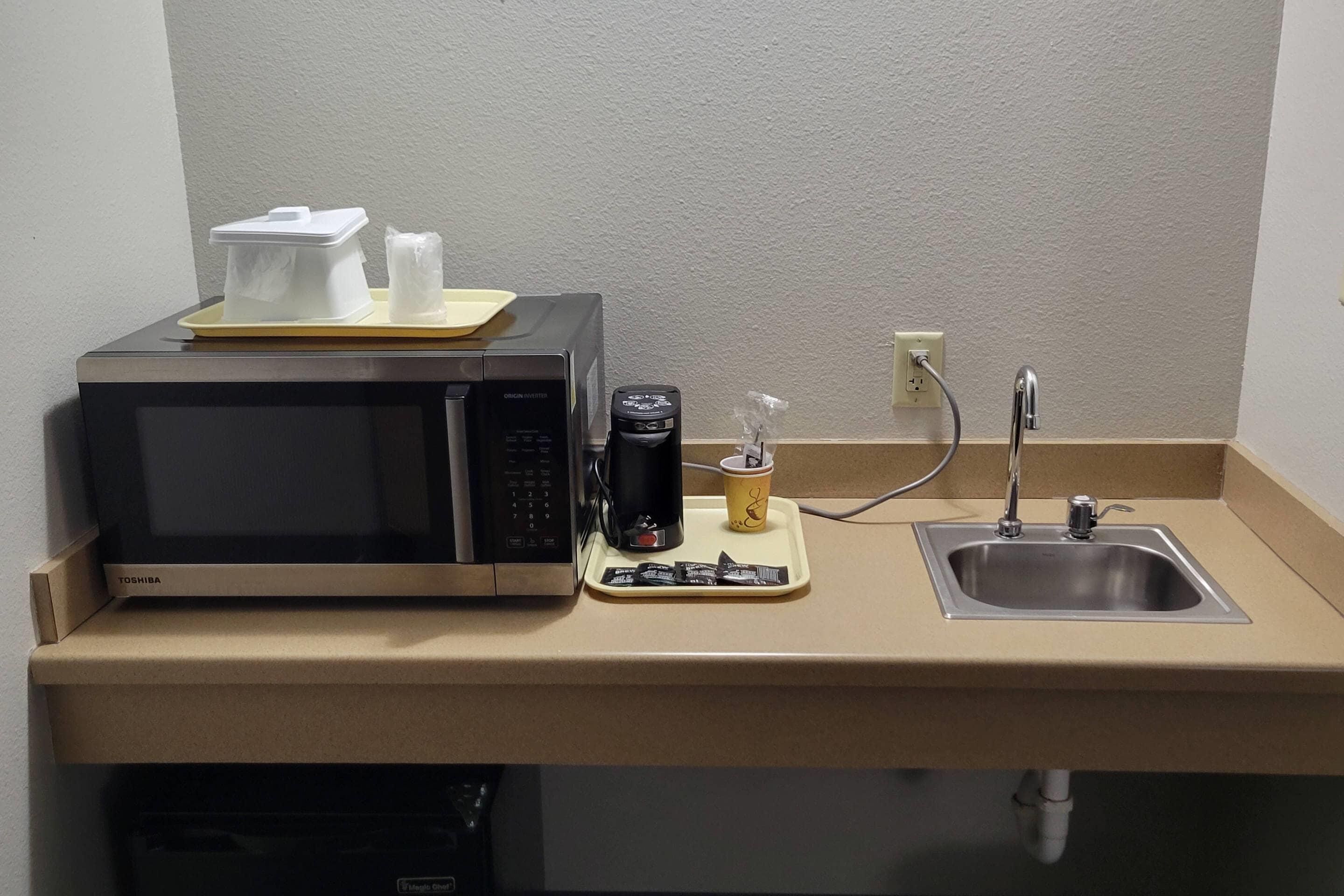 Una kitchenette equipada con microondas, cafetera y lavamanos.
