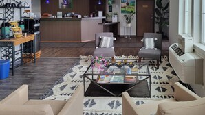 A hotel lobby with a reception desk, seating area, coffee machine, and a large window. - Quality Inn & Suites Pinedale (Pinedale)