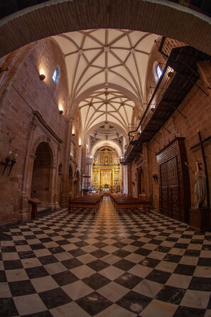 A church interior with a checkered floor, arched ceilings, and a central altar. - Hotel Palacio Guzmanes (Banos De La Encina)