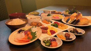 A dining table with various dishes, including sushi, vegetables, and bread.