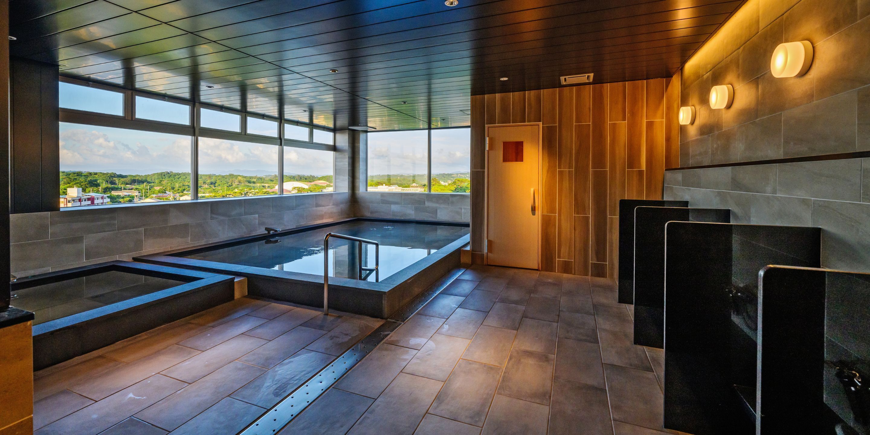 A modern indoor pool area with clear views of the outdoors, a wooden ceiling, and a tiled floor.