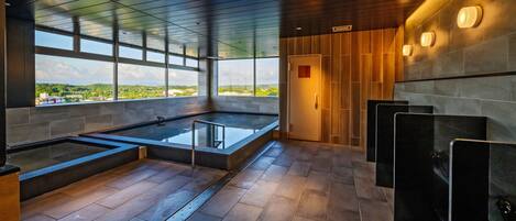 Un área de piscina interior moderna con vistas despejadas al exterior, techo de madera y suelo de baldosas.
