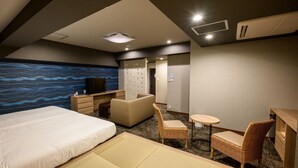 Una camera d'albergo con un letto, una scrivania, una sedia, un tavolino e una parete con un motivo a onde blu.