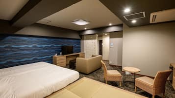 Ein Hotelzimmer mit Bett, Schreibtisch, Stuhl, einem kleinen Tisch und einer Wand mit blauem Wellenmuster.