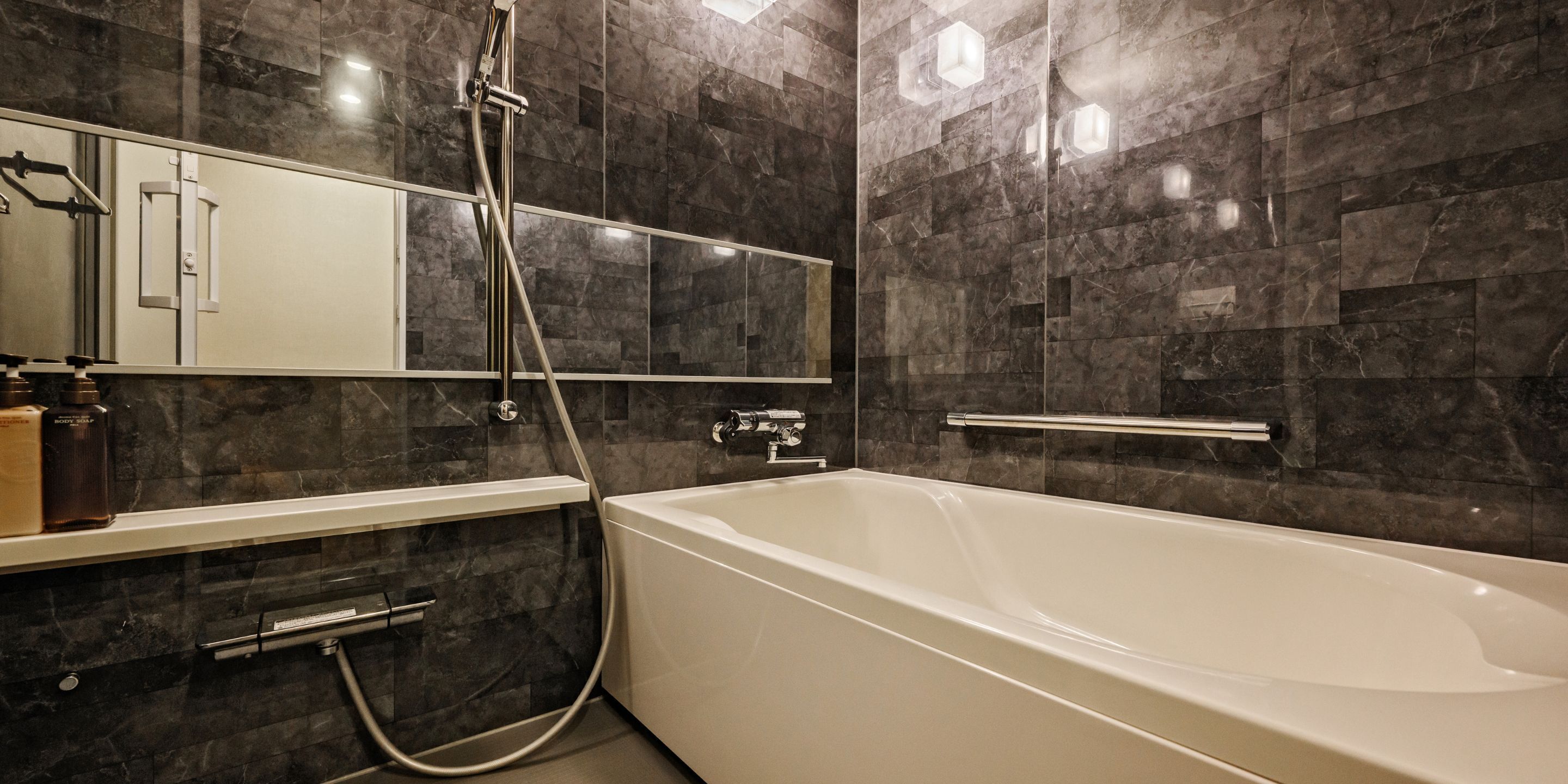 Une salle de bain moderne avec une baignoire sur pieds, une douche en verre et un mur recouvert de carreaux de marbre.