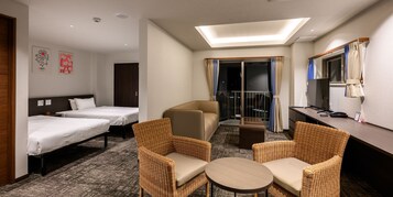 Habitación de hotel con dos camas individuales, un sofá, dos sillas de mimbre, una mesita pequeña, un escritorio con ordenador y un balcón con cortinas.