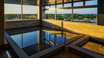 Un spa moderno con un amplio jacuzzi de vidrio y vistas al paisaje circundante, con suelo de madera.