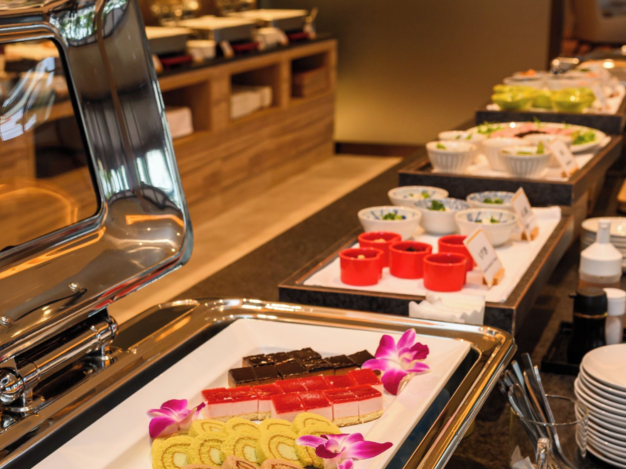 A buffet setup with various food items and a tray of desserts.