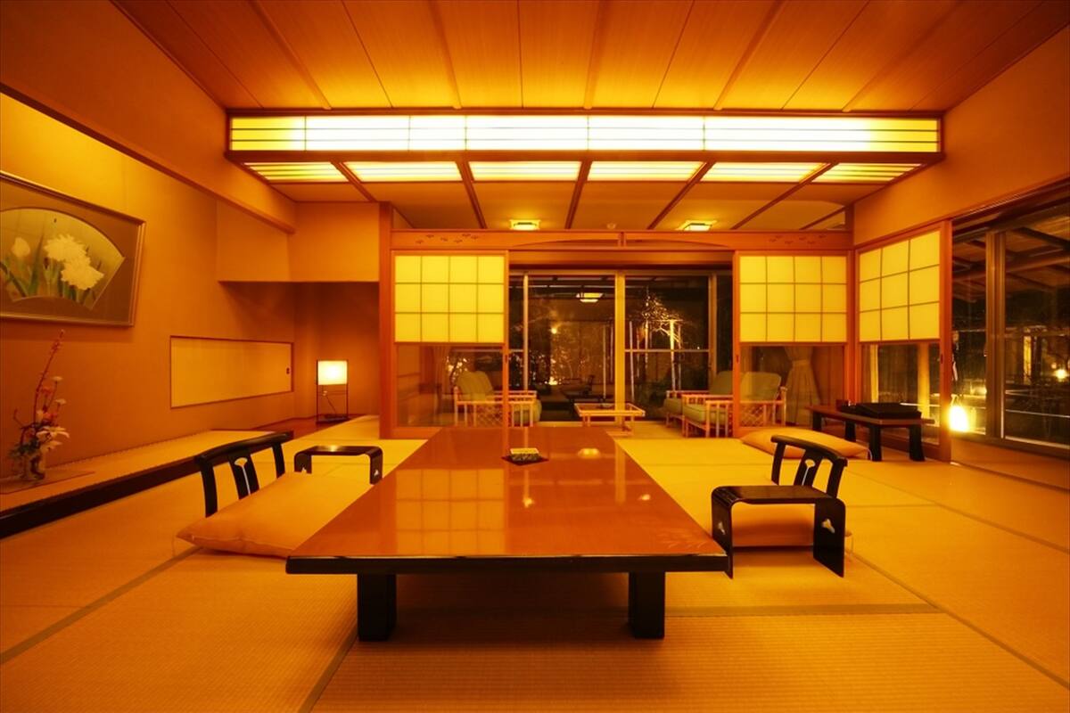 A traditional Japanese-style room with tatami flooring, a low table, and chairs.