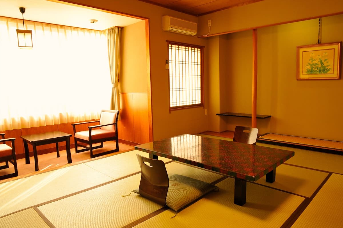 A traditional Japanese room with tatami flooring, a low table, and sliding doors.
