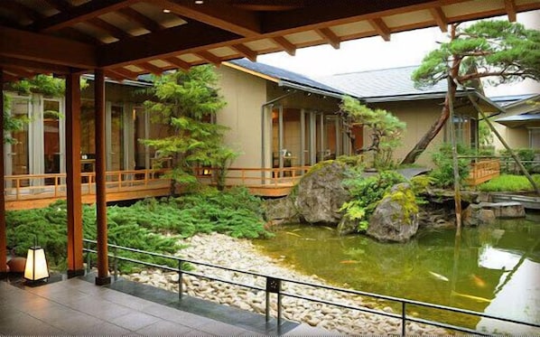 Un jardín tradicional japonés con un estanque de carpas, puentes de madera y un farol de piedra.