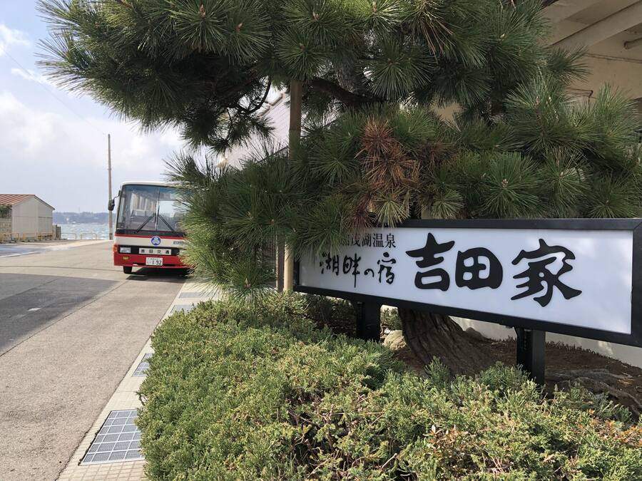 Un letrero con caracteres japoneses, un autobús y follaje.