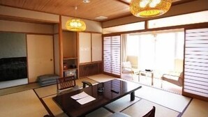 A traditional Japanese room with tatami flooring, a low table with cushions, and sliding doors. - Kohan no Yado Yoshidaya (Sado)