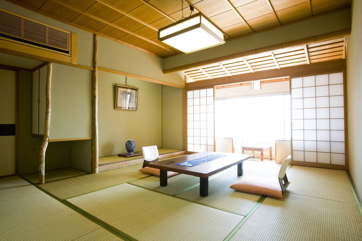Una habitación japonesa tradicional con suelo de tatami, una mesa baja y puertas correderas.