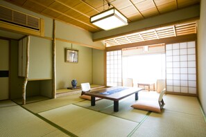 Une pièce de style japonais traditionnel, avec un sol recouvert de tatamis, une table basse et des portes coulissantes.