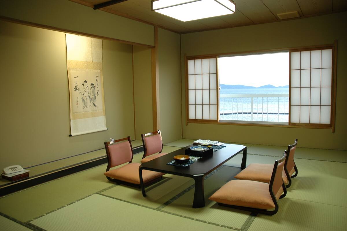 Una habitación japonesa tradicional con suelo de tatami, una mesa baja y puertas correderas shoji.