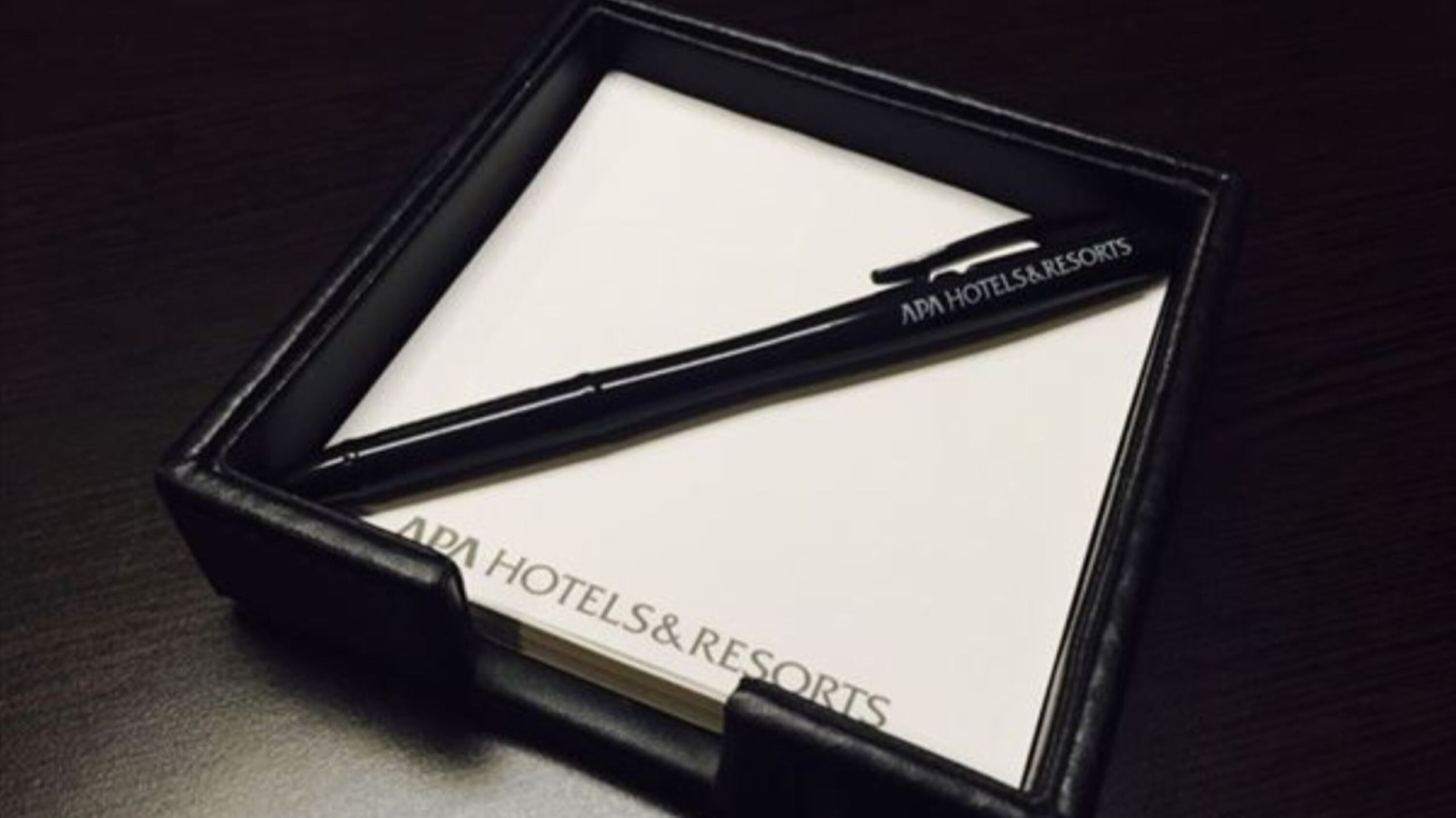 Ein schwarzer Stift mit der Aufschrift "APA HOTELS & RESORTS", platziert auf einem weißen Blatt Papier in einer schwarzen Schachtel.