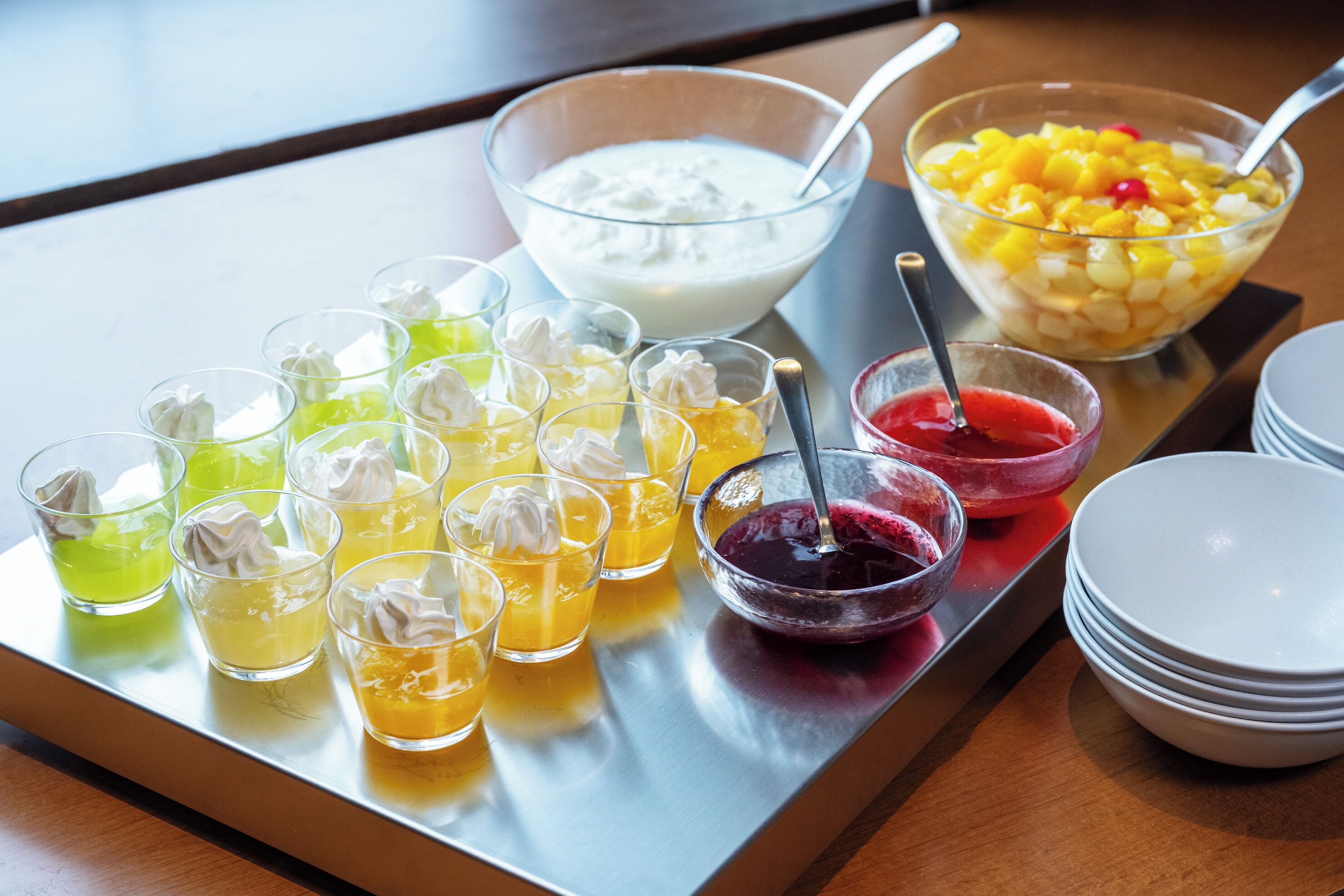 Una bandeja con diversas bebidas y un bol de ensalada de frutas.